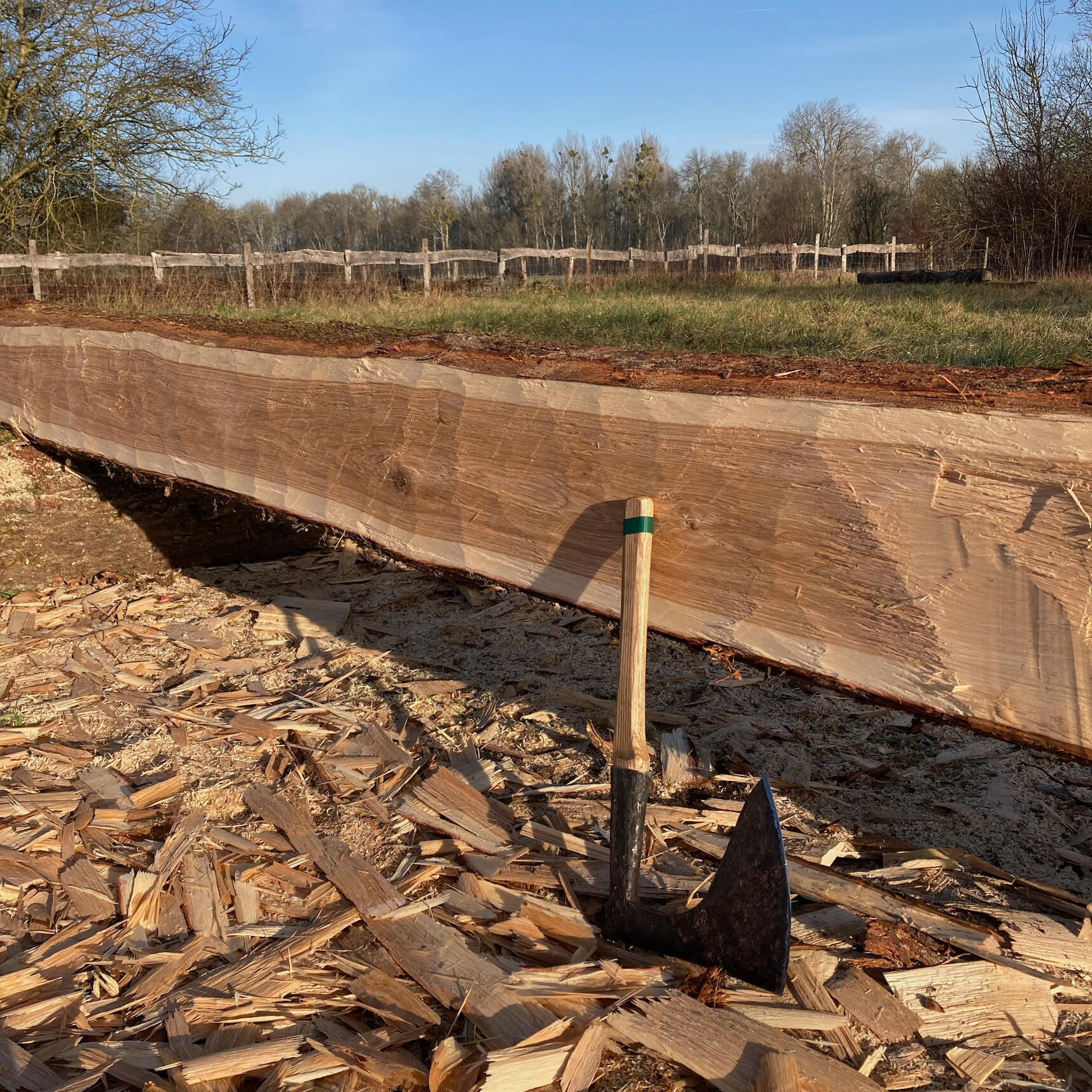 detail of hand hewn texture on oak beam and the historic axe used to make the surface quality